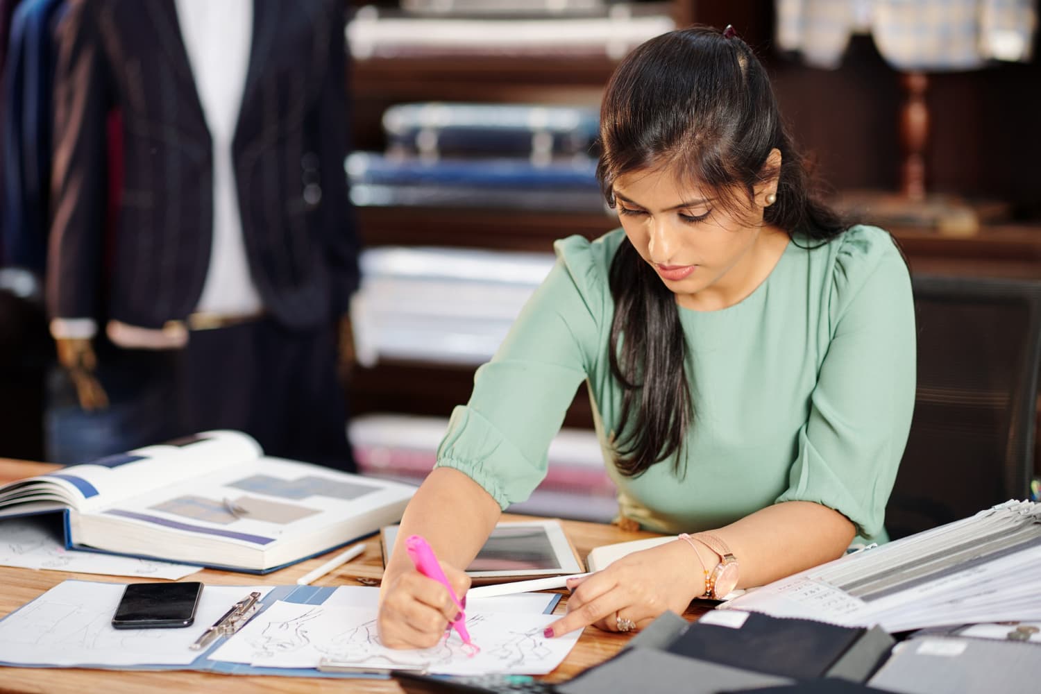 A teacher surrounded by paper registers and scattered notes, looking overwhelmed